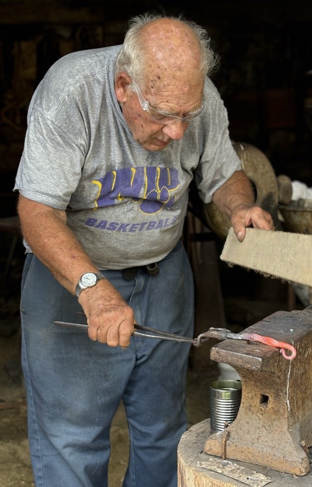Portrait of artist Paul Rohrbach at his anvil